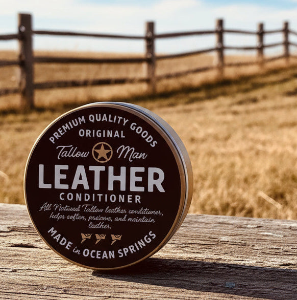 Front-facing Tallow Man Leather Conditioner tin on a warm cream background.
